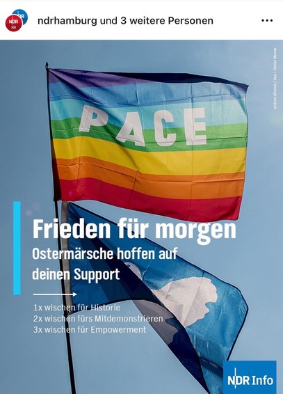 Eine Regenbogen-Friedensflagge mit dem Wort "PACE" weht über einer anderen Flagge vor einem blauen Himmelshintergrund. Textüberlagerung in Deutsch und das NDR Info-Logo sind ebenfalls sichtbar.