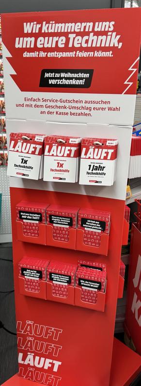 Ein Ausstellungsständer, der für Technologie-Support-Geschenkgutscheine wirbt. Der Stand umfasst verschiedene Serviceoptionen für technische Unterstützung vor Ort, z.B. „1 Jahr Technikhilfe“